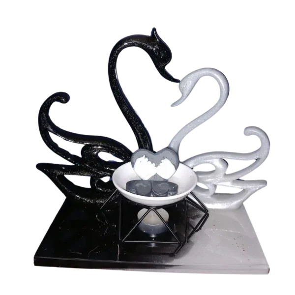 2 cygnes noir et blanc en résine accompagner d'un brûleur de fondants parfumés La coupelle est composée d'un fondant cœur avec 2 mains liées et de 4 petits fondants cœur