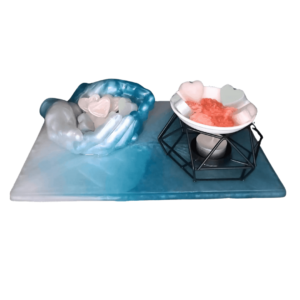 Plateau rectangle en résine époxy, avec un contenant de deux mains jointes, ainsi qu’un brûleur pour fondant.
